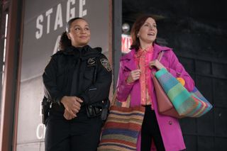 Carra Patterson as Kaya Blanke in her police uniform and carrie preston as elsbeth in a pink trench holding various bags entering a tv studio in a still from elsbeth