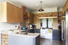 A kitchen with oak wall cupboards and dark grey sprayed units