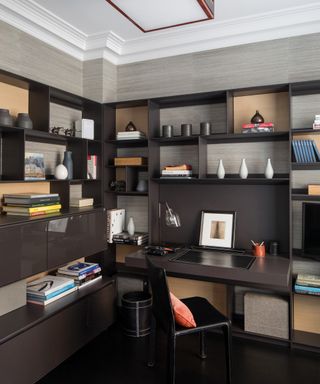 A study with dark brown open shelving and taupe walls