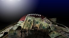 A football is barely visible under a pile of cash under stadium lights.