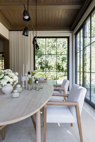 Modern sunroom with wooden dining table and black windows