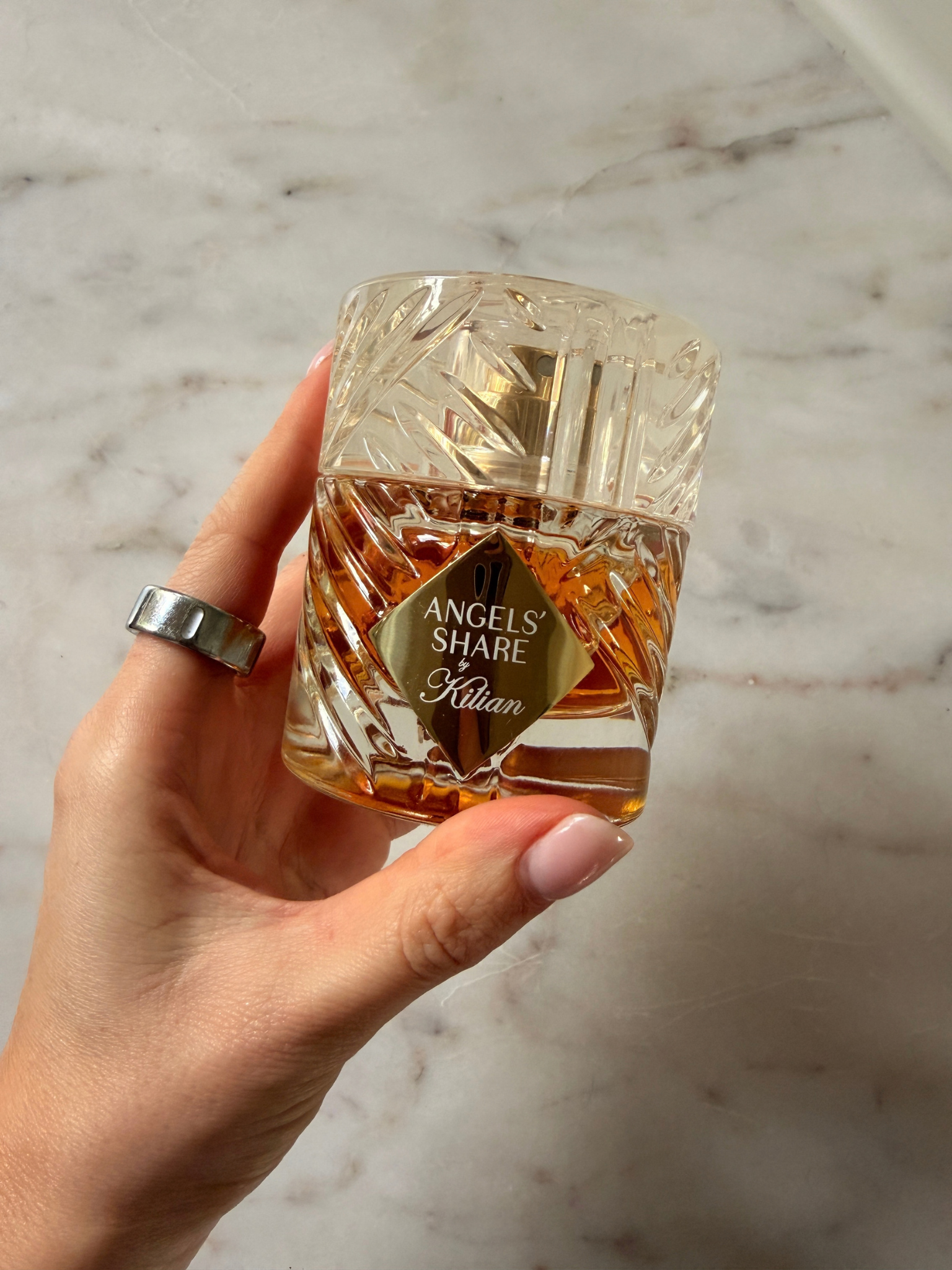 Freelance beauty editor Grace Day holding a bottle of Kilian Paris Angels&amp;rsquo; Share Eau De Parfum
