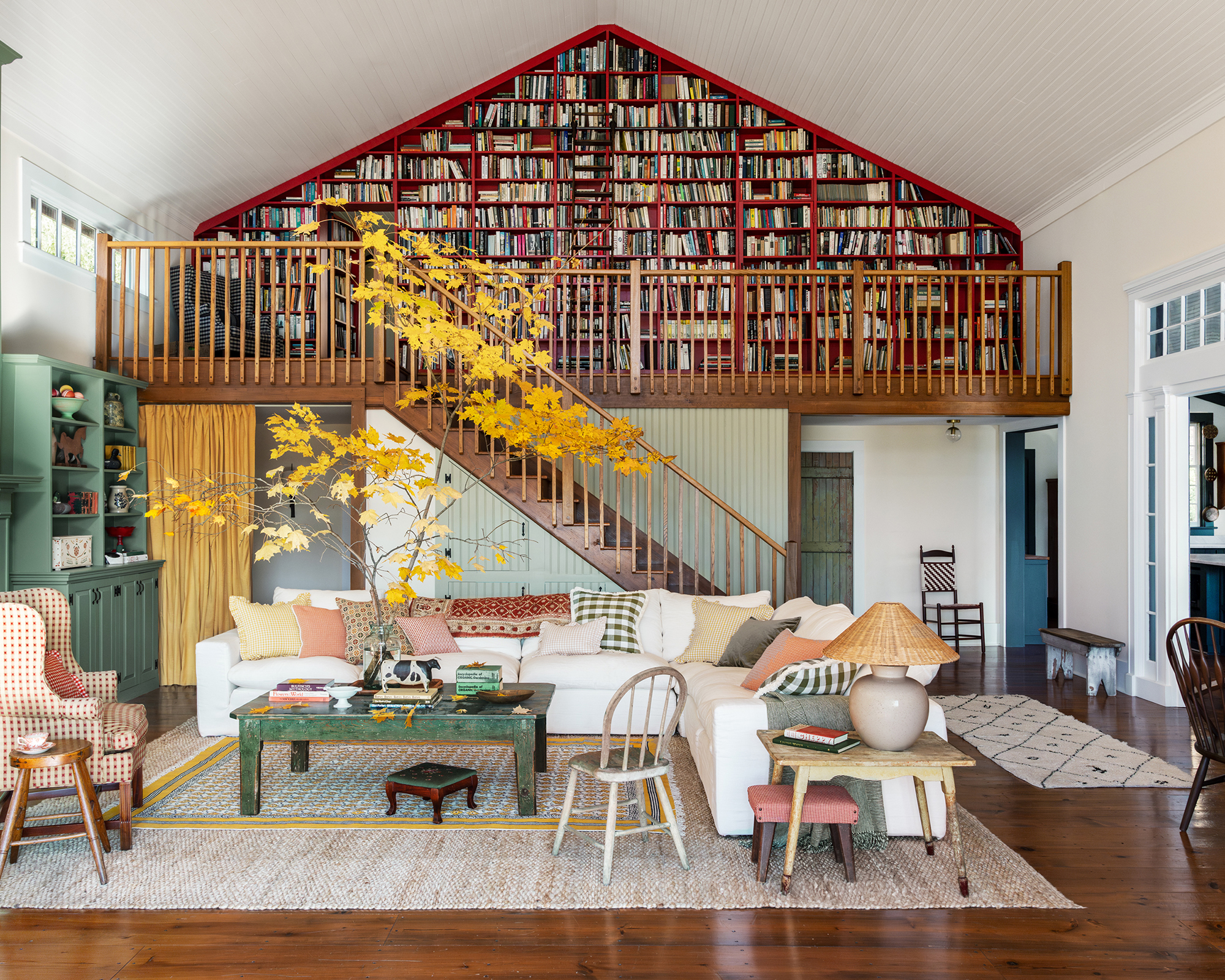 living room with white sofa and staircase behind leading to a library on a mezzanine level