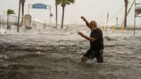 A man crosses a storm surge flooded area on the coast of Gulfport, Fla. as Hurricane Helene passed through the Gulf of Mexico to the West on September 26, 2024.