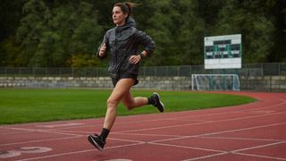 Woman running on track wearing Garmin Forerunner 255