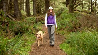 Female hiker walking her dog in the forest