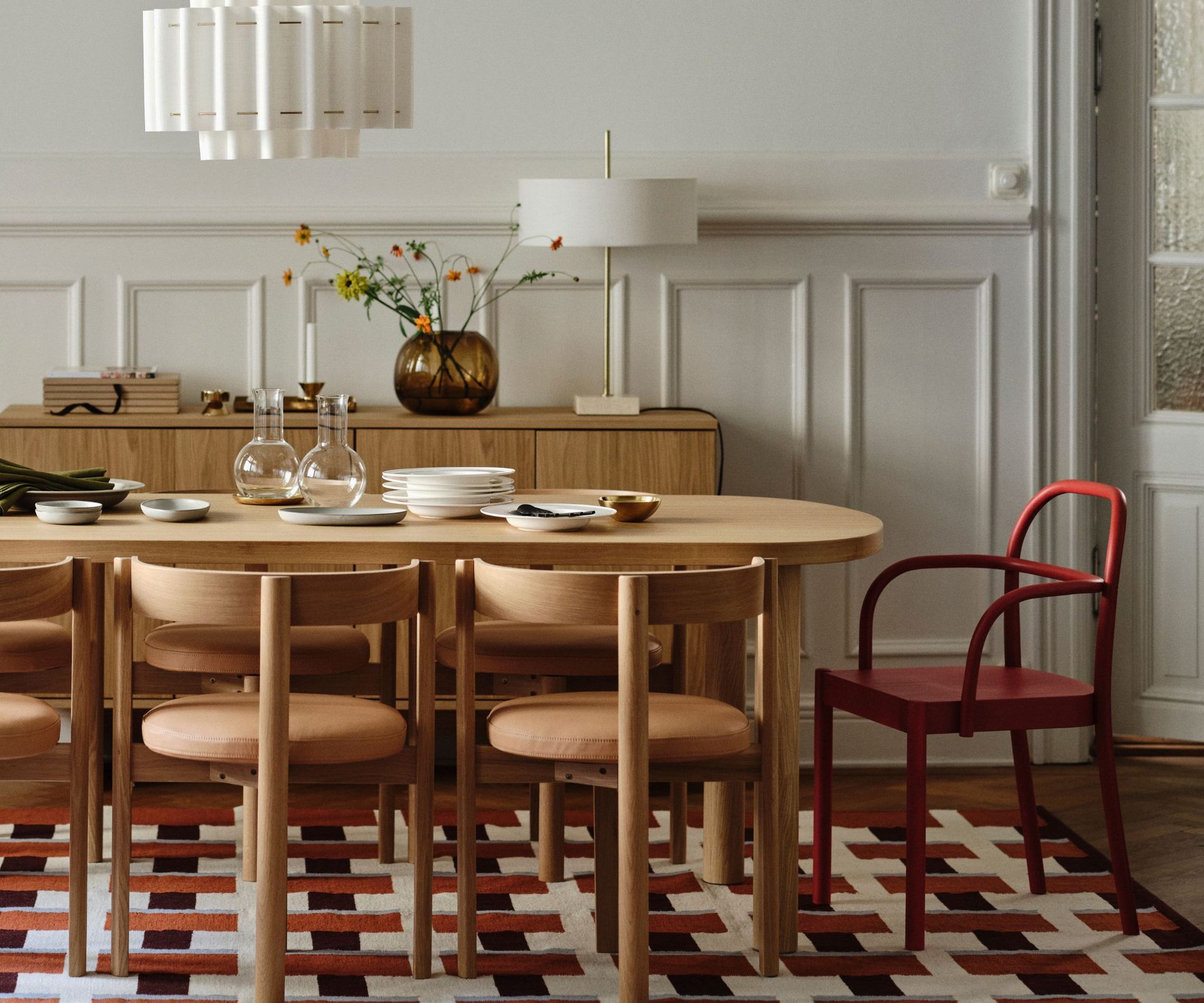 Dining room with orange geometric rug, wood dining table and red chair