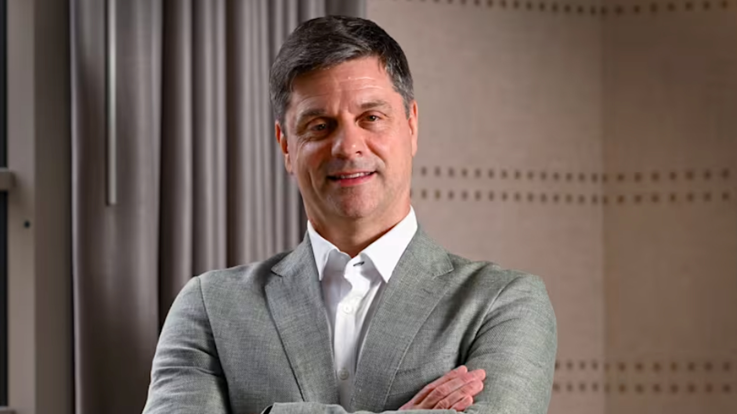 A headshot of new PGA Tour CEO, Brian Rolapp wearing a grey suit with his arms crossed
