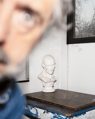 a still life of a bust on a table with Alec Soth in the foreground out of focus