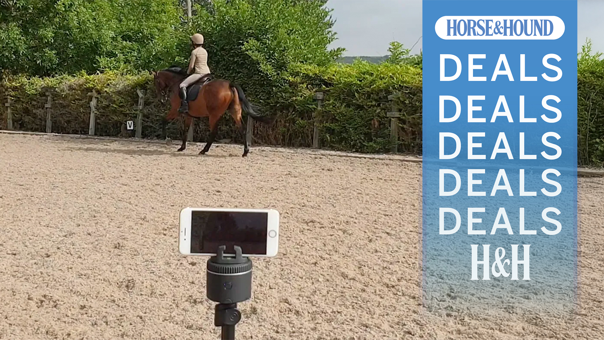 Women riding bay horse in arena with smartphone attached to a Pivo Equestrian Pod filming in the foreground