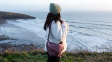 woman wearing the peak design sling bag at a coastal location