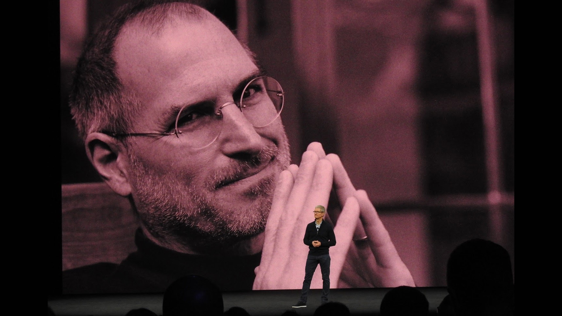 Tim Cook under image of Steve Jobs