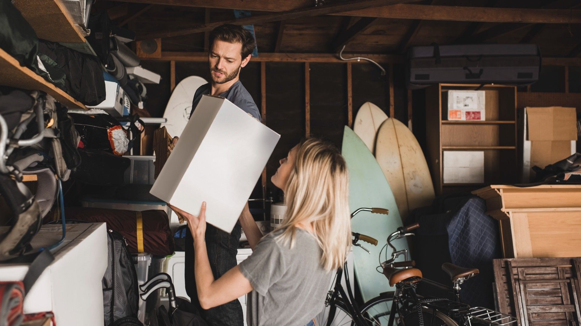 couple moving boxes up into storage in a garage