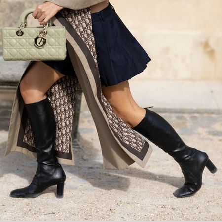 woman wearing black knee high boots and dior scarf and bag