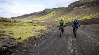 Lael Wilcox and Jenny Graham cycling along a gravel road in Iceland
