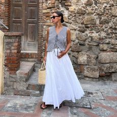 Woman wears gingham top, white skirt, black sandals