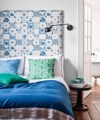 A guest bedroom with a blue and white patterned headboard and a functional wall light