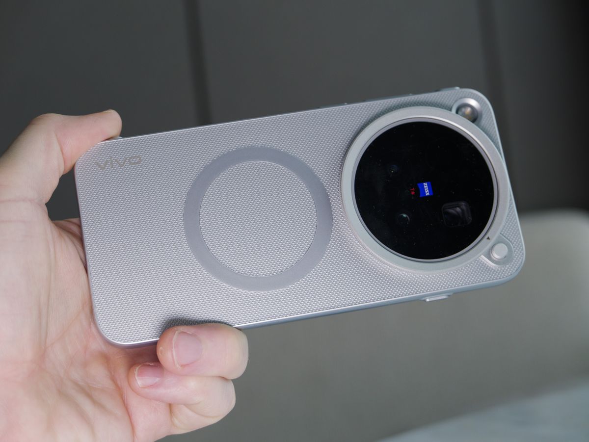 The Vivo X500 Pro Max phone in user's hand, indoors, in its dedicated case for magnetic accessories such as Vivo's selfie screen