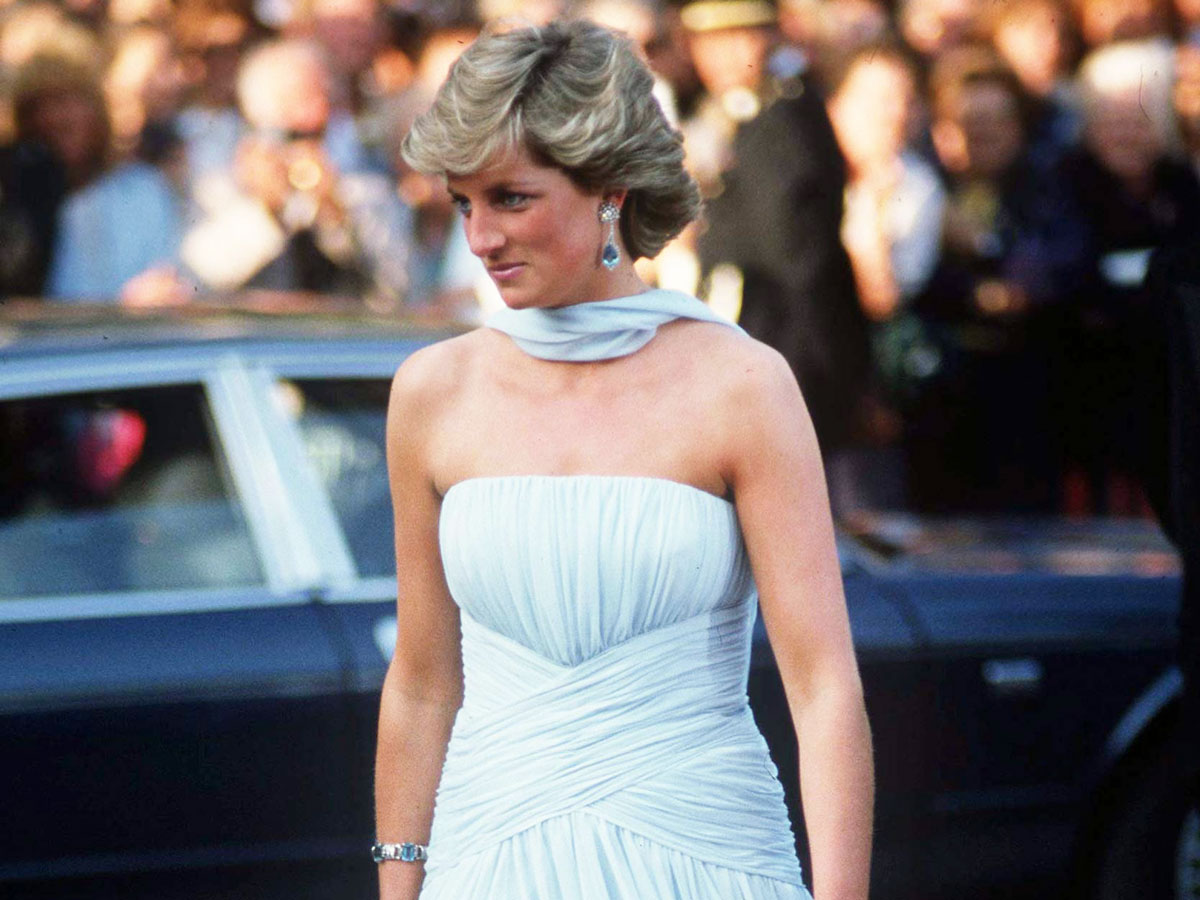 Princess Diana at the Cannes Film Festival wearing a blue strapless dress with a sash around the neck.