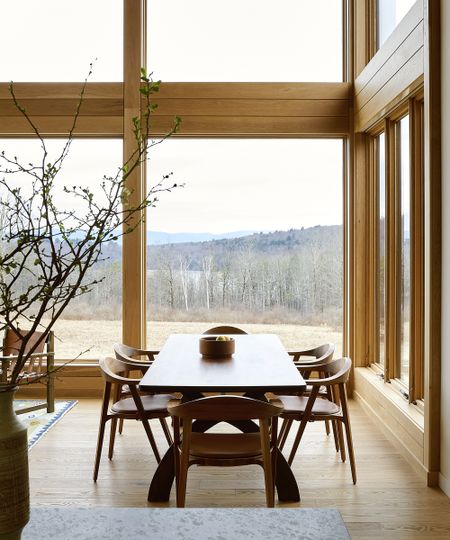 wood dining table in a wood framed room with big windows