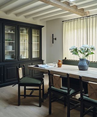 wooden dining table with upholstered chairs and glass fronted storage cabinets