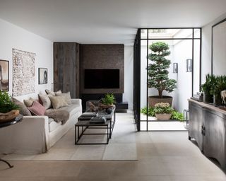 Basement small living room lighting ideas in a sleek, neutral scheme with courtyard garden and beige sofa.