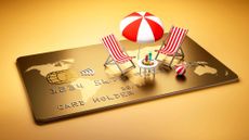 Beach chairs with table and cocktails and umbrella on a large golden credit card 