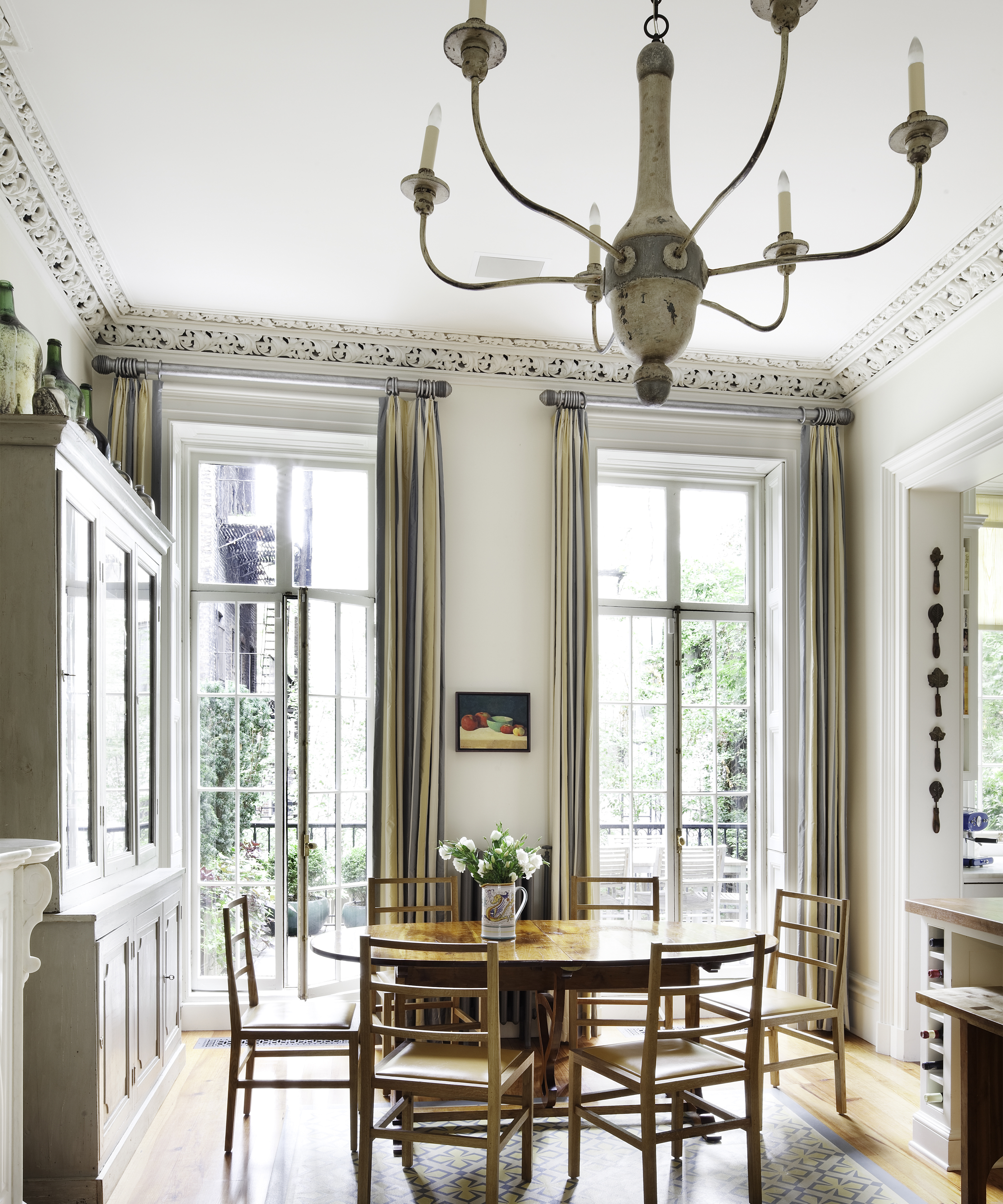 dining table in the corner of a large cream kitchen with an antique chandelier
