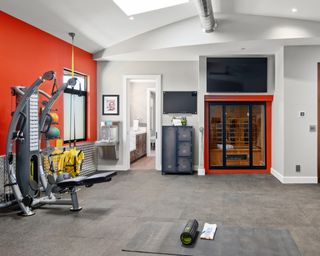 A home gym with orange wall and home sauna setup