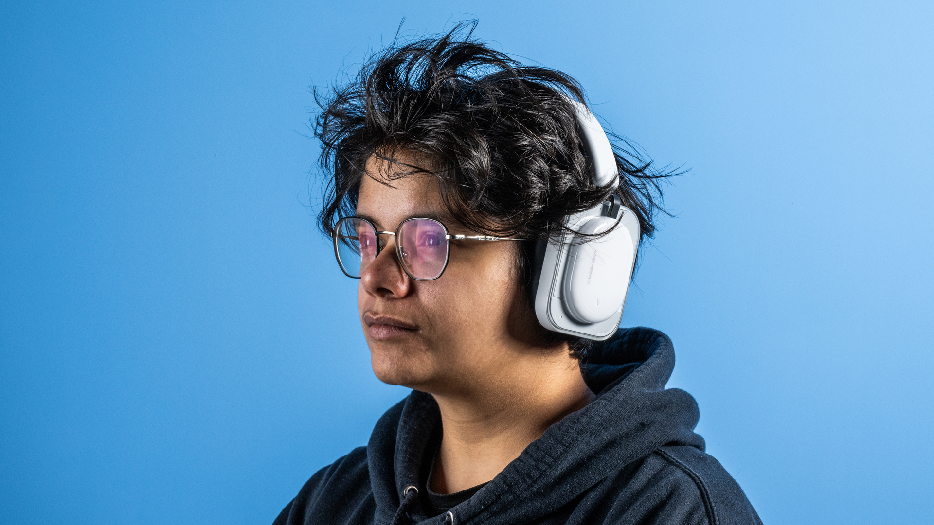 the nothing headphone (a) photographed against the blue tom's guide background, showing the transparent and white ear cups with red accents, the padded headband, and the accessories including 3.5mm jack