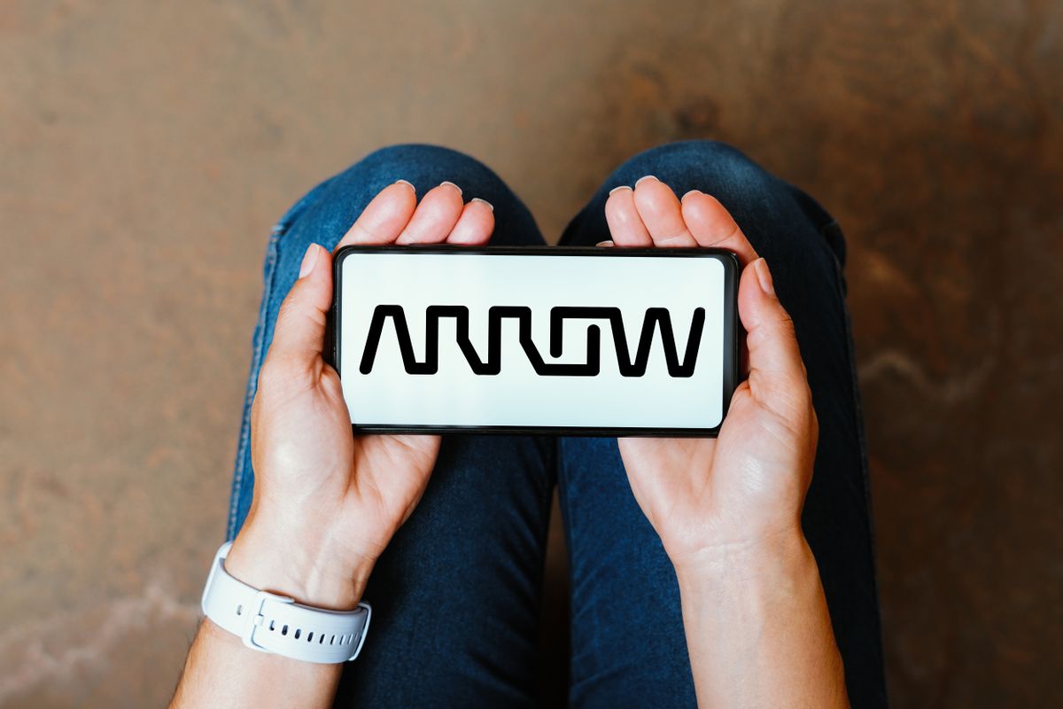 Arrow Electronics logo on a smartphone held in the palms of two two open-faced hands resting on a sitting person&#039;s lap