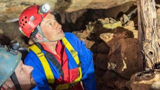 Jamie Lund, an archaeologist, and Ed Coghlan, a caving club leader, explore mines beneath Alderley Edge. They are both wearing a hardhat with a light and a safety harness and are looking up.