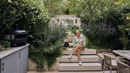 a woman and a dachshund in a modern garden surrounded by purple planting 
