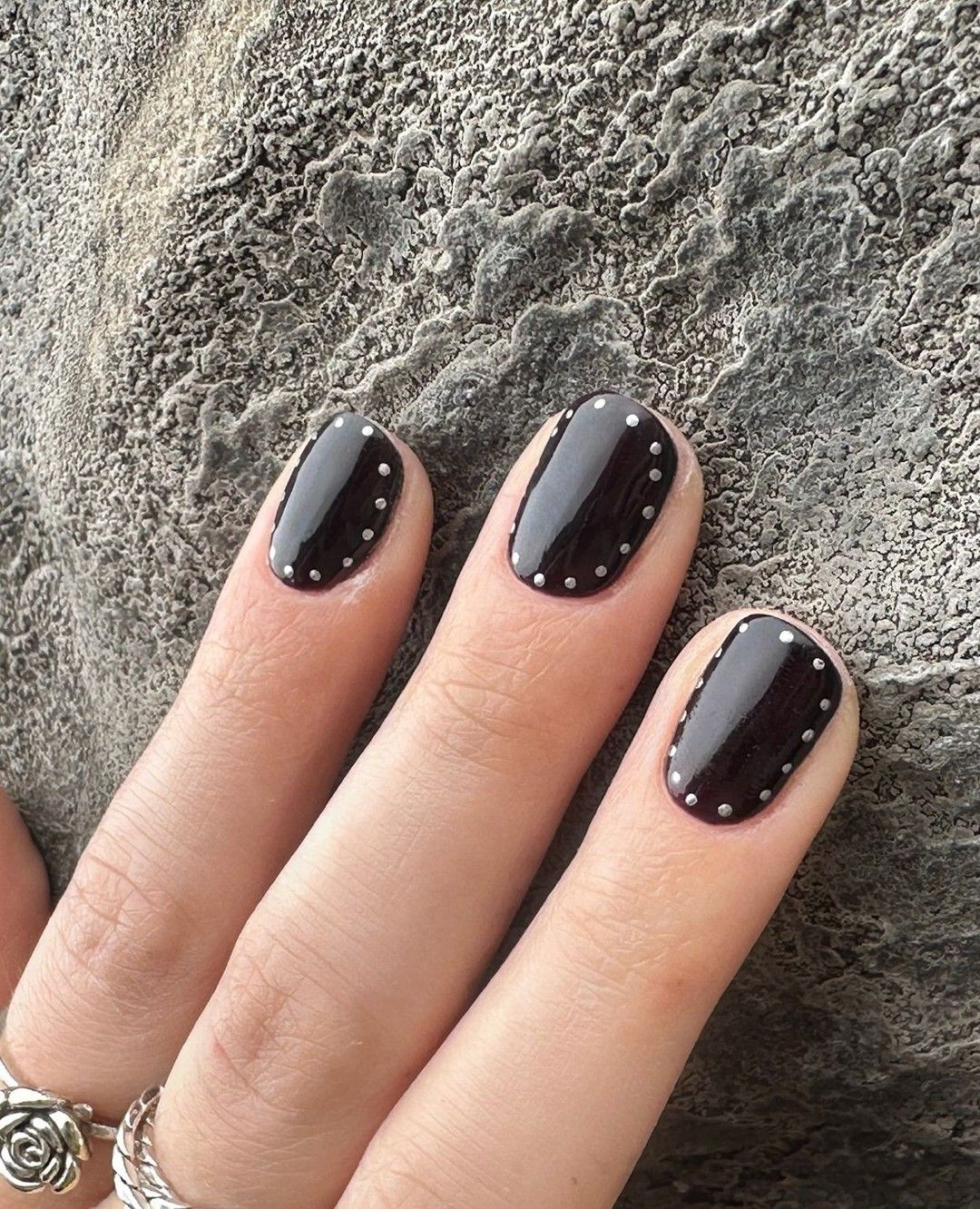 Black nail polish with silver dots.