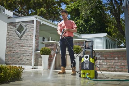 man cleaning a drive with Ryobi RPW120B High Pressure Cleaner