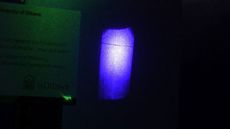 A green laser beam inside a ruby crystal casts a horizontal shadow when illuminated by blue light.