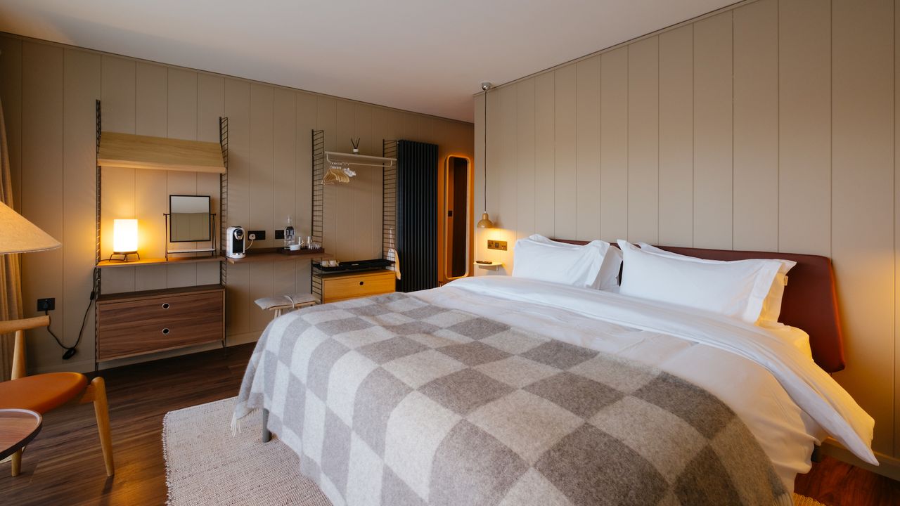A hotel bedroom with wood panelled walls and a large double bed with crisp white sheets