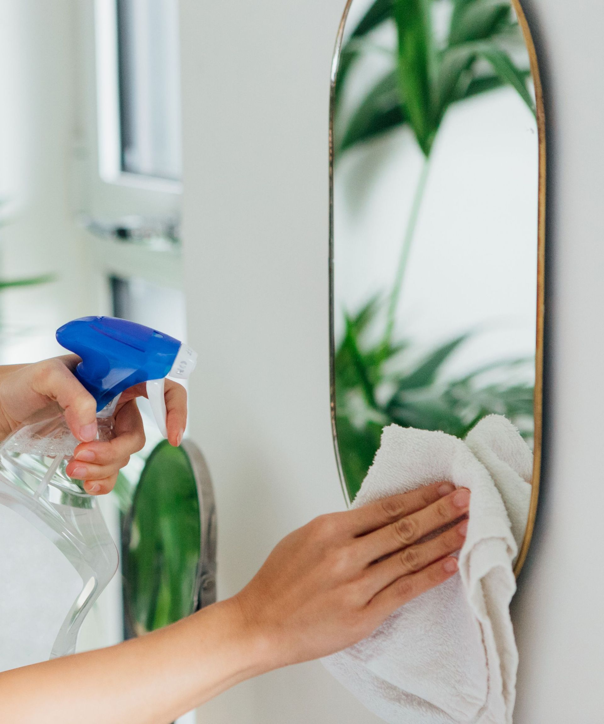 Someone spraying a wiping a mirror