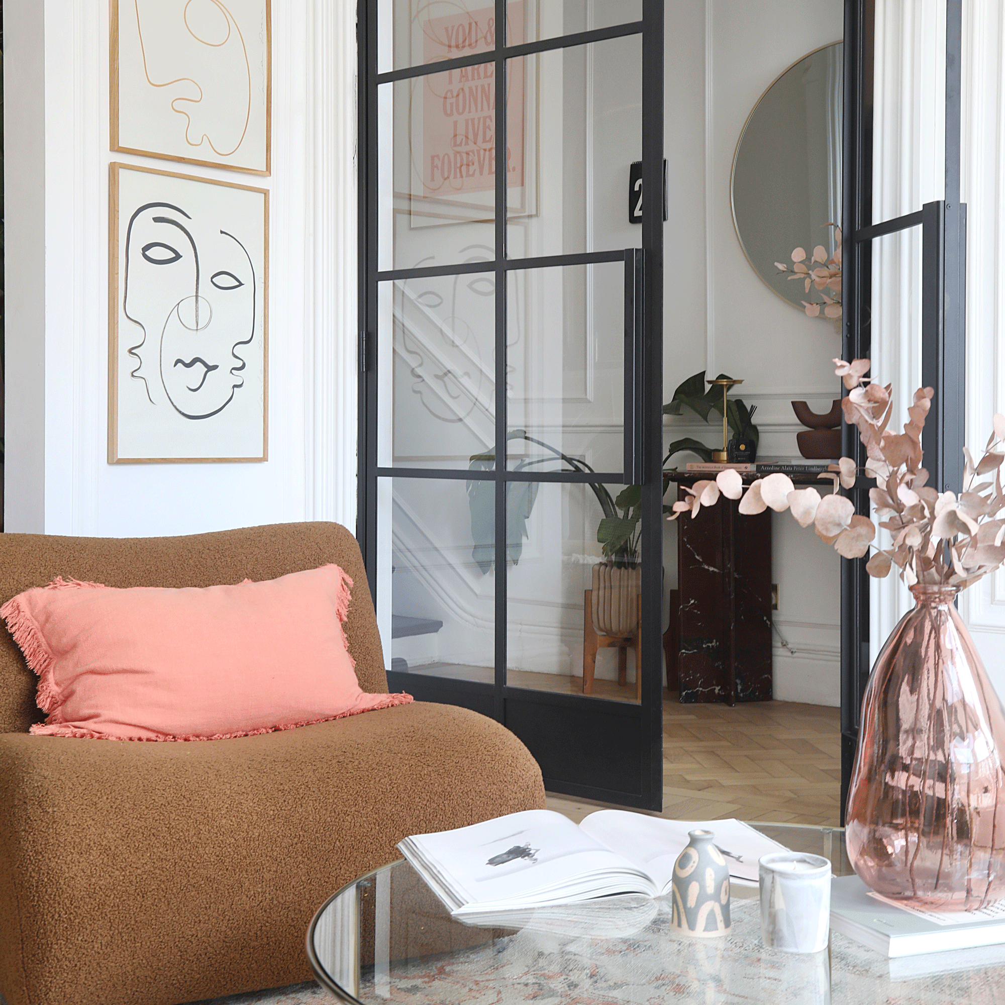 a living room with curved sofa and and internal glazed door leading into a hallway