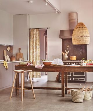 Concrete kitchen flooring costs in an earthy pale pink and rattan scheme.