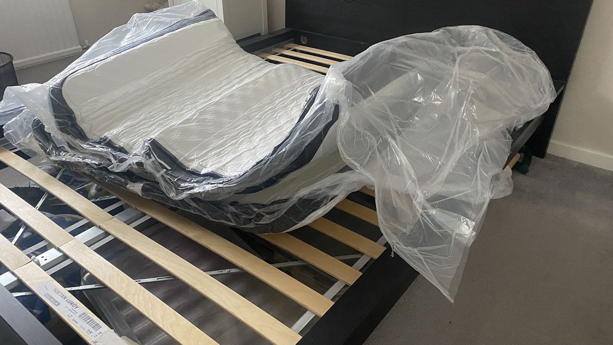 The Plank Firm Mattress starting to unroll on the reviewer's bed frame