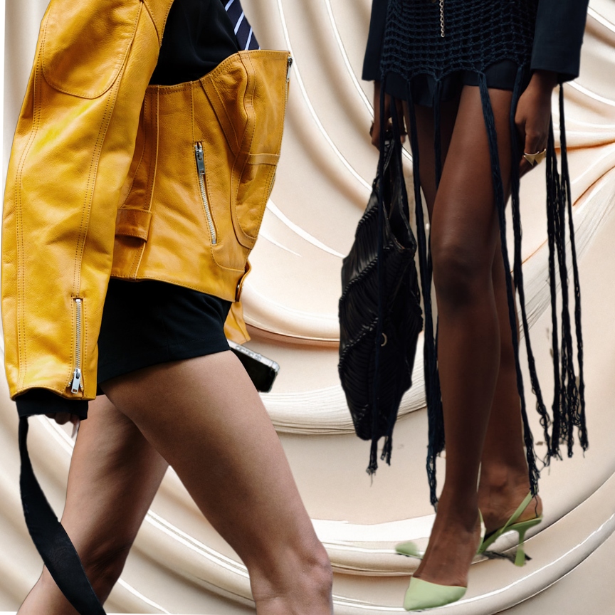 a creamy background with two women's legs, one wearing black shorts and a yellow leather jacket and the other is wearing a knit black skirt and green heels