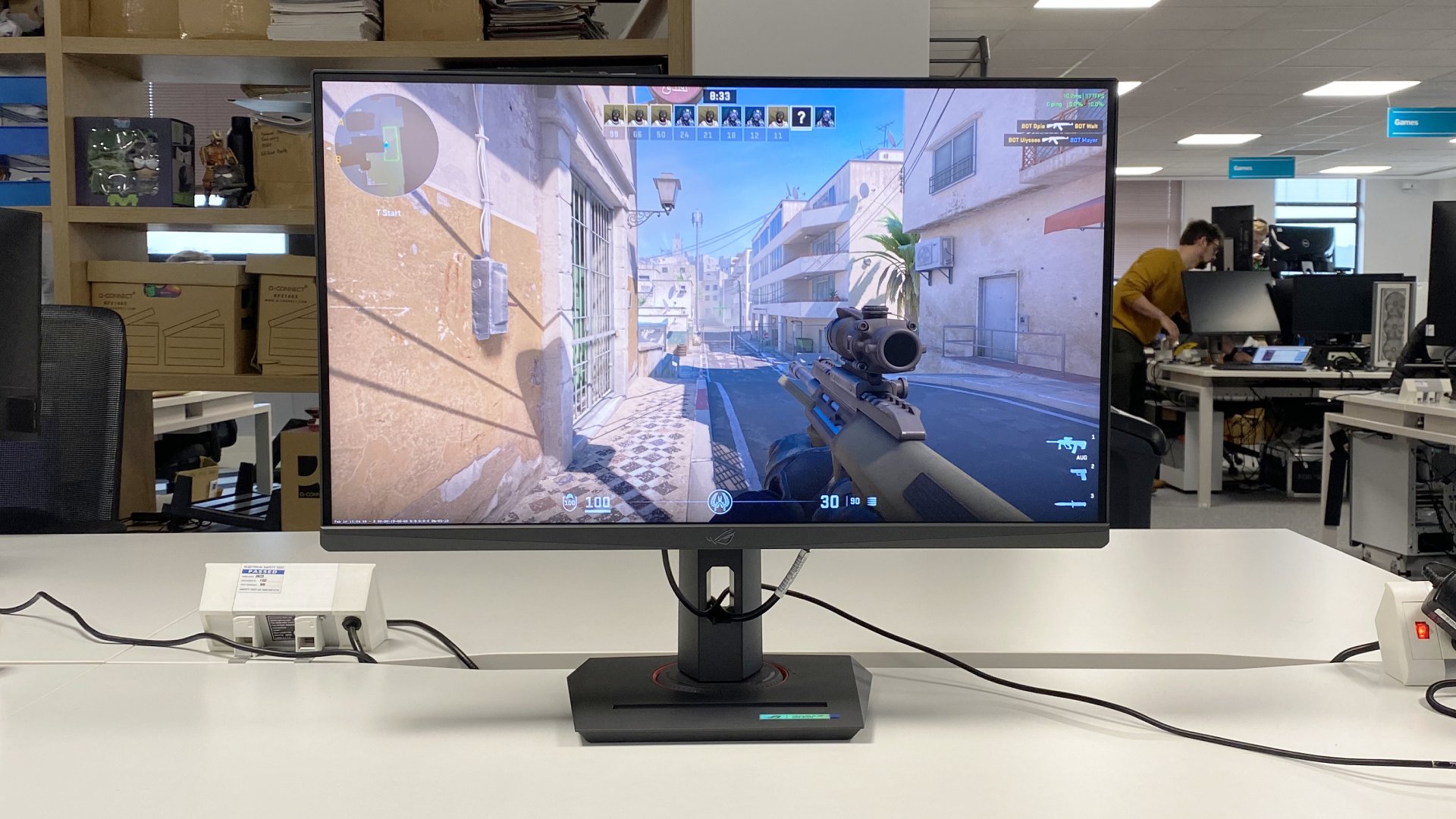 The Asus ROG Strix XG27ACS gaming monitor on a white desk.