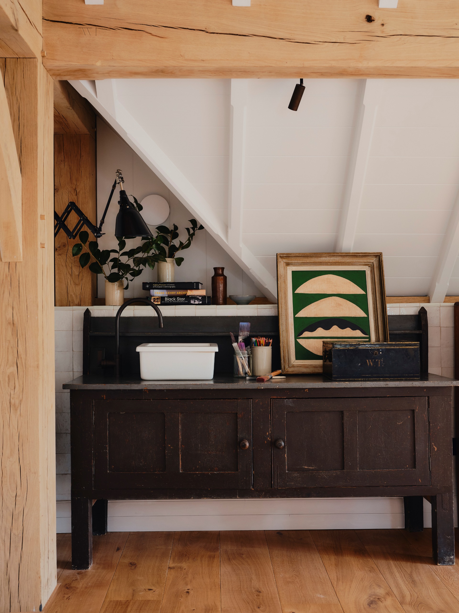 A house nook in a loft conversion, decorated with wood of all types and abstract decor along with objects like books and utensils.