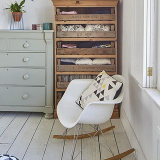 Light room with rocking chair, rustic wood storage shelves and a duck egg blue chest of drawers