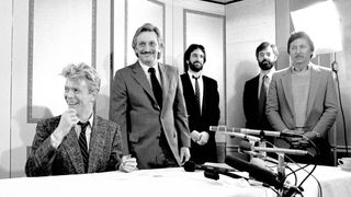 View of British Rock musician David Bowie (1947 - 2016) (seated, left) as he signs a contract while unidentified EMI record executives watch at the Carlyle Hotel, New York, New York, January 27, 1983. He was there signing a worldwide recording deal (worth $17.5 million dollars) with EMI Records upon the expiration of his prior contract (with RCA).