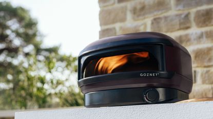 Gozney x Tonester pizza oven in front of stone wall