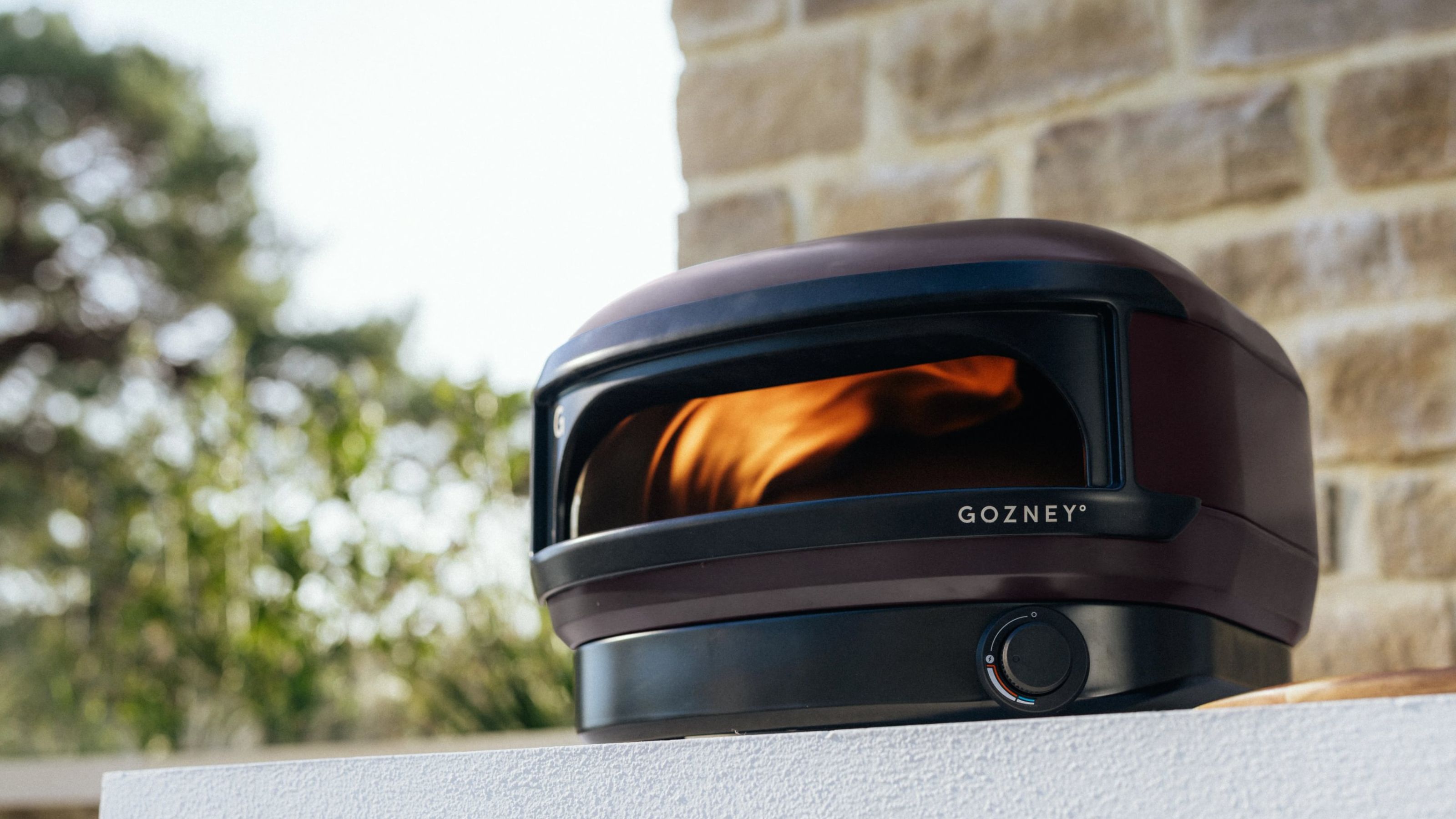 Gozney x Tonester pizza oven in front of stone wall