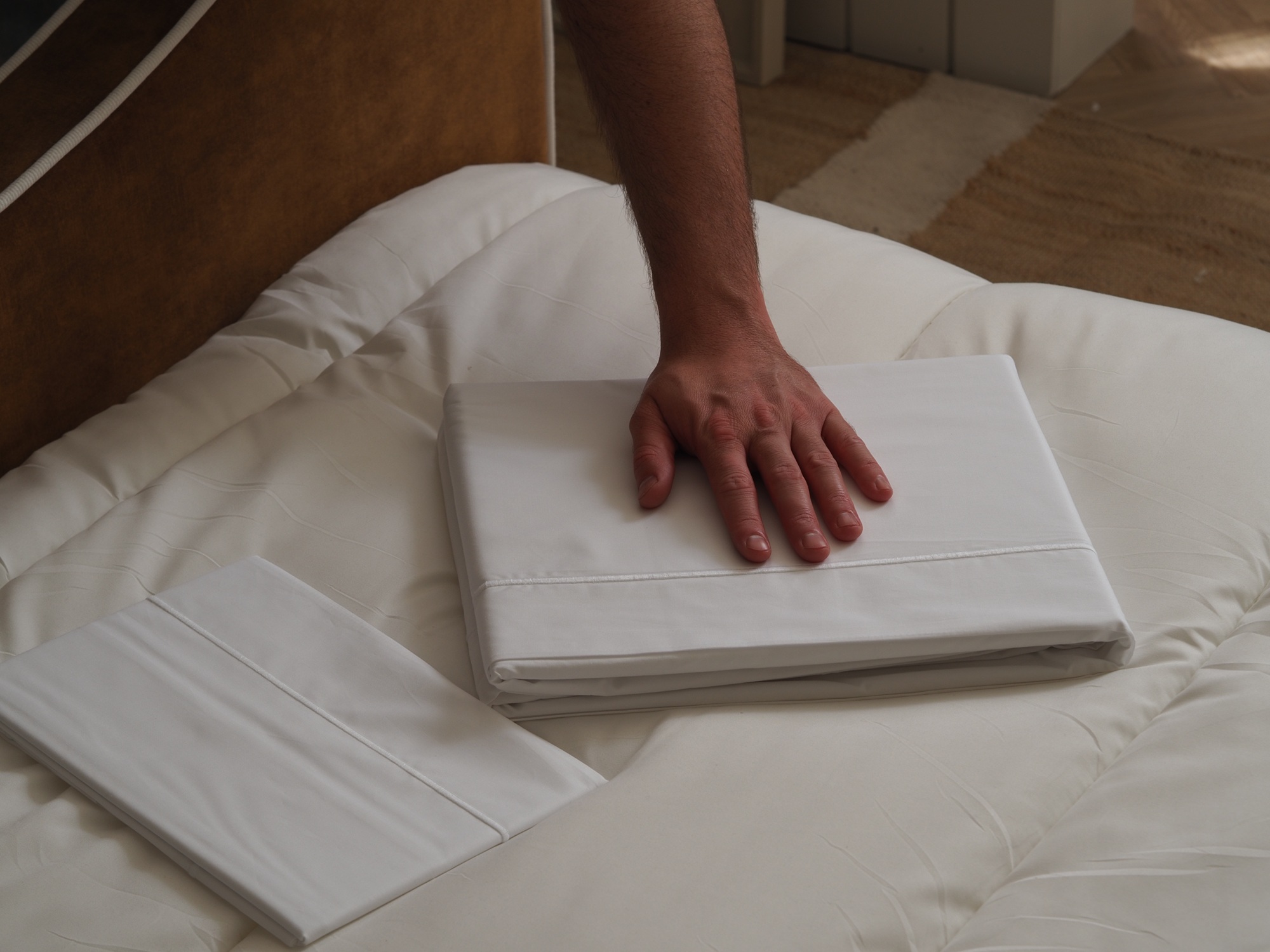 hand touching white company bedding on a bed