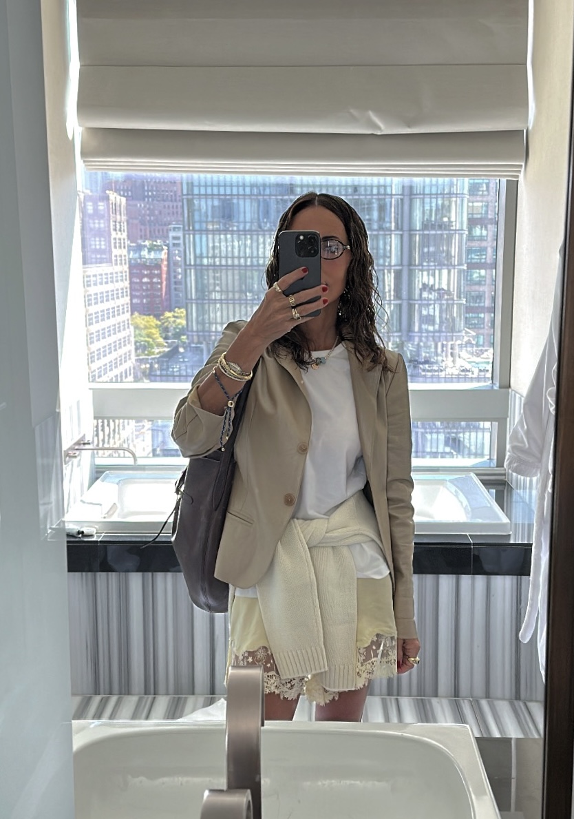 Larissa Mills wearing a white tee, tan blazer, lace shorts, and cream sweater around her waist